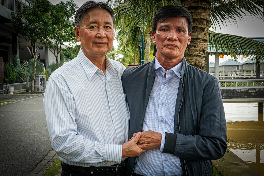 Two Asian men standing next to each other shaking hands.