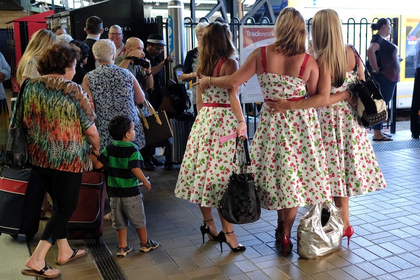 Women dressed in 50s outfits pose for photos before boarding the train to the annual Parkes Elvis Festival