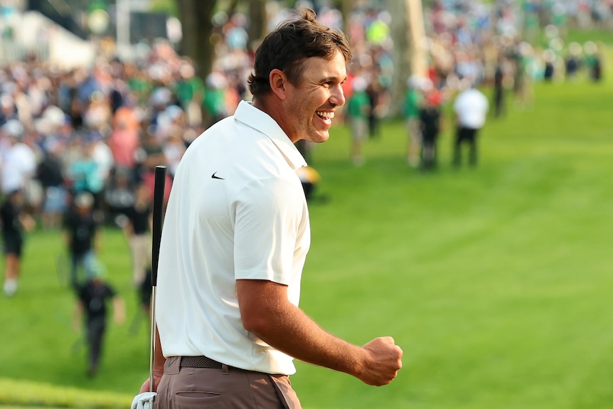Brooks Koepka smiles and pumps his fist on the 18th green