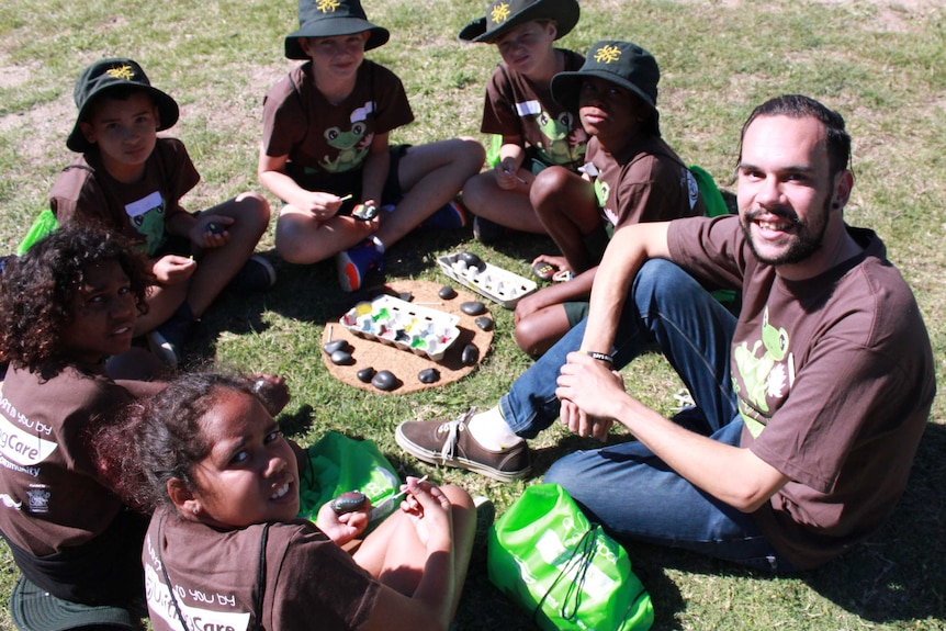 James Mundy with a group of Indigenous children sitting in a circle