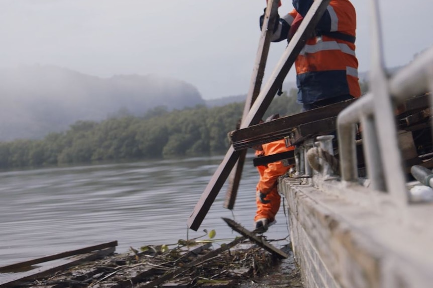 Man in high-vis removes wood from jetty