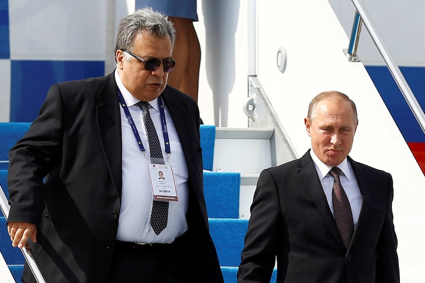 Russian Ambassador to Turkey Andrey Karlov (L) accompanies Russian President Vladimir Putin who disembarks from the Presidential aircraft at Ataturk airport in Istanbul, Turkey