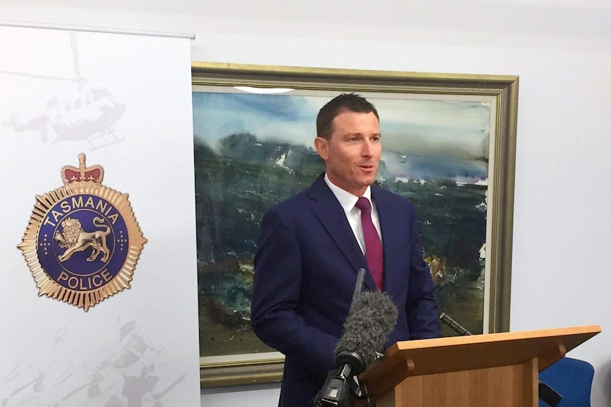 Tasmania Police Detective Inspector Craig Joel stands at a podium and talks to the media.