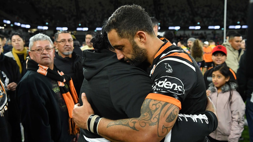 A male NRL player hugs a family member after playing his 300th first grade match.