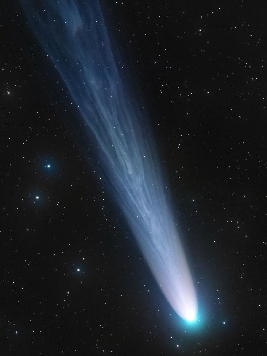 Un cometa con un chorro de luz saliente se dirige hacia abajo a la derecha de la foto. 