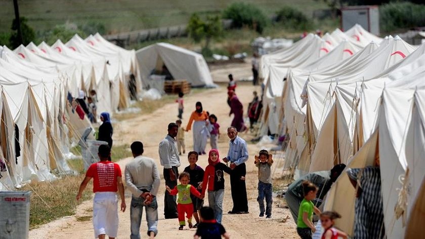 Refugees walking among white tents