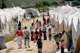 Refugees walking among white tents