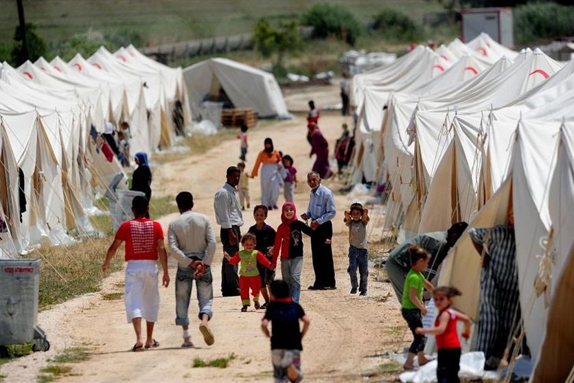 Refugees walking among white tents