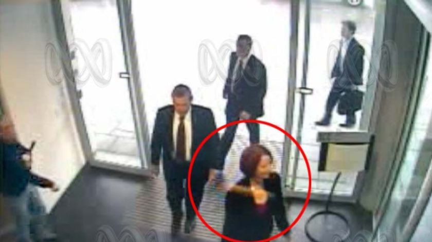 An egg flies past Prime Minister Julia Gillard (bottom) after a man (left of frame) allegedly threw it at her inside the ABC Perth studios.