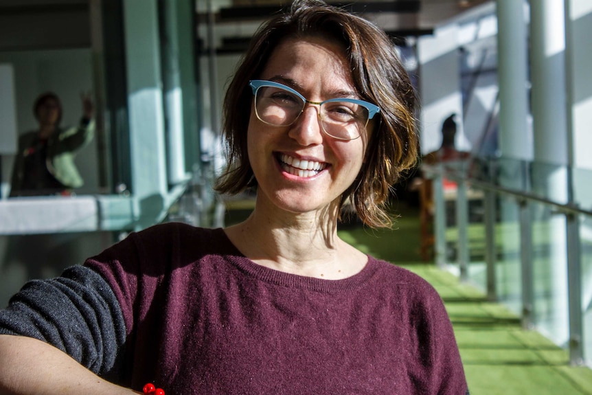 Alice Zaslavsky stands in a hallway smiling with the sun on her face.