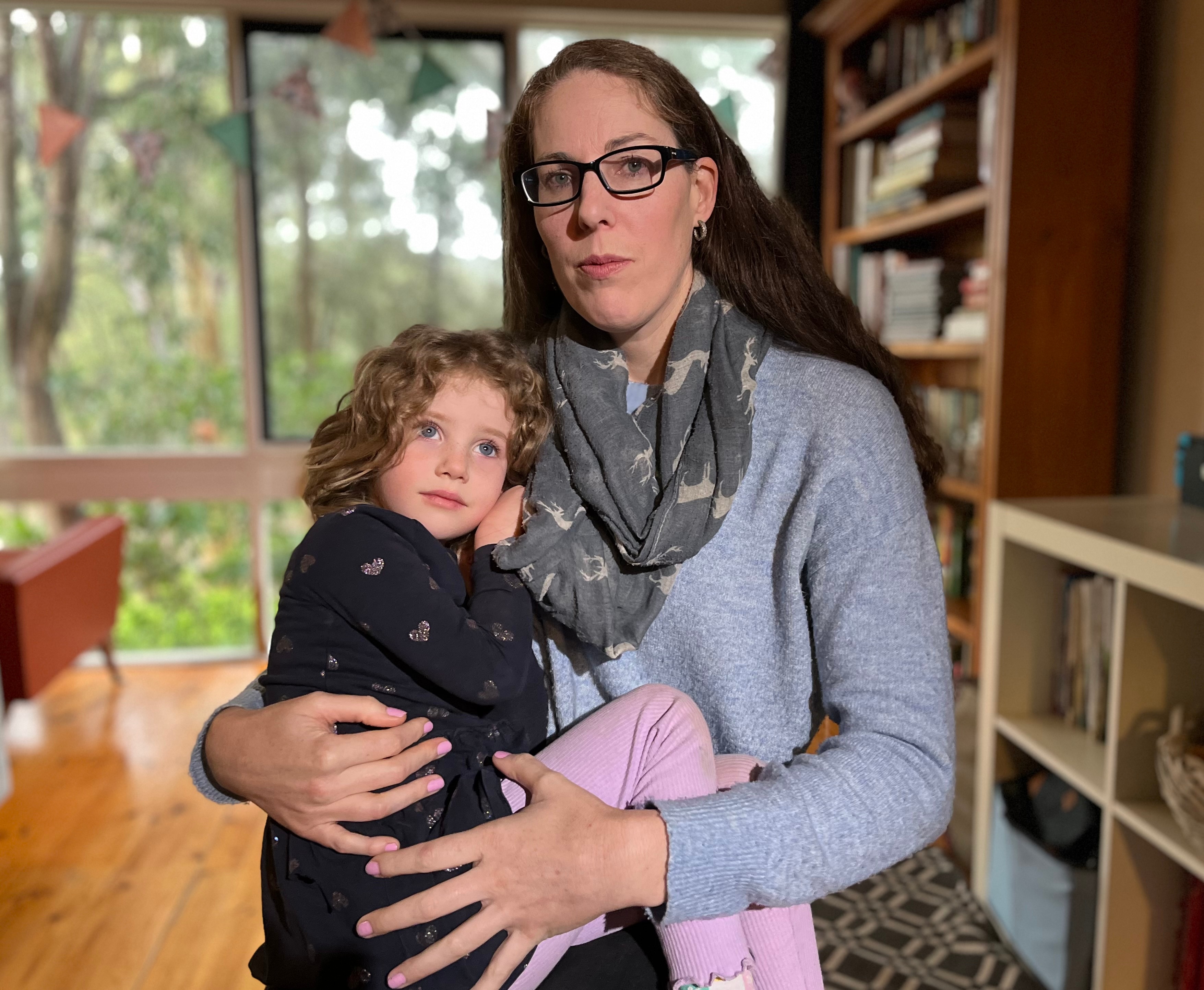 Laura wearing a grey jumper, holding her four-year-old daughter in her arms.