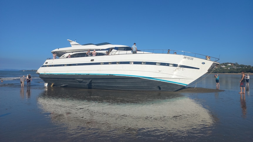 A large boat sitting on shoreline of a beach