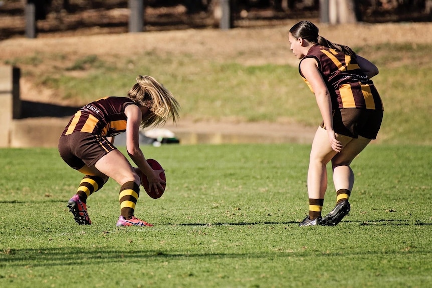 Two players during a suburban Australian rules football game.