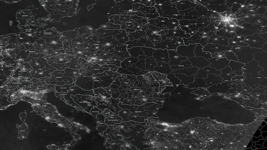 Ukraine is seen in darkness in a greyscale satellite image indicating the night radiance of Europe