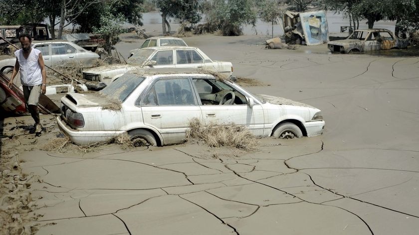 A Pakistani flood survivor walks past cars stuck in mud after flash floods in Nowshera