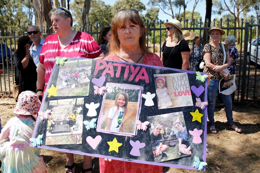 A woman holding a large poster with the name 'Patiya', which is covered in photos, news clippings, and paper cut-outs.