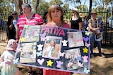 A woman holding a large poster with the name 'Patiya', which is covered in photos, news clippings, and paper cut-outs.