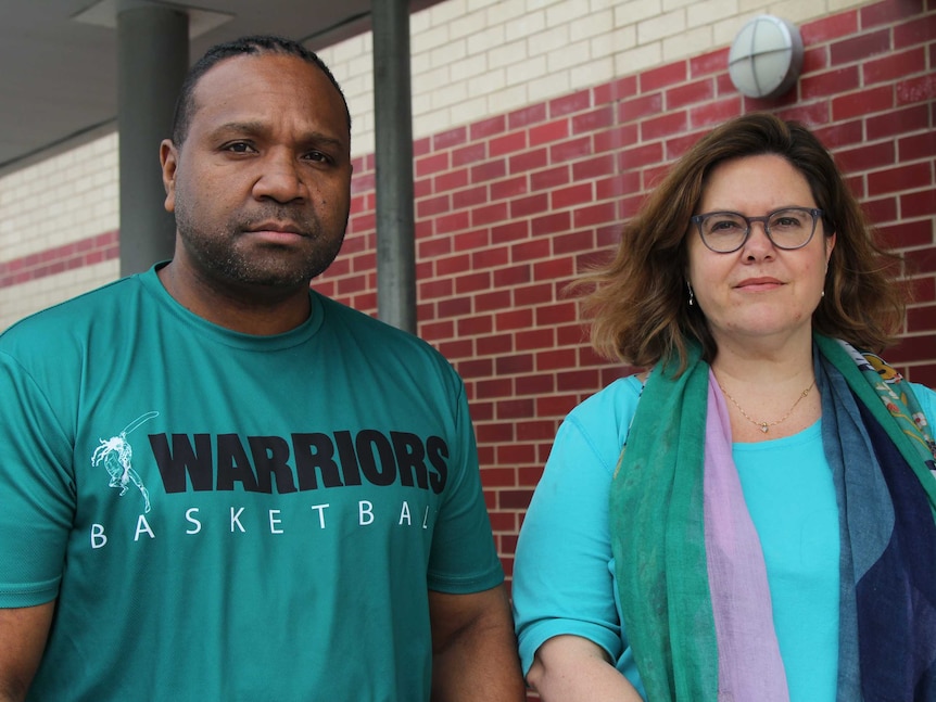 Parents of young sports people outside a basketball court.