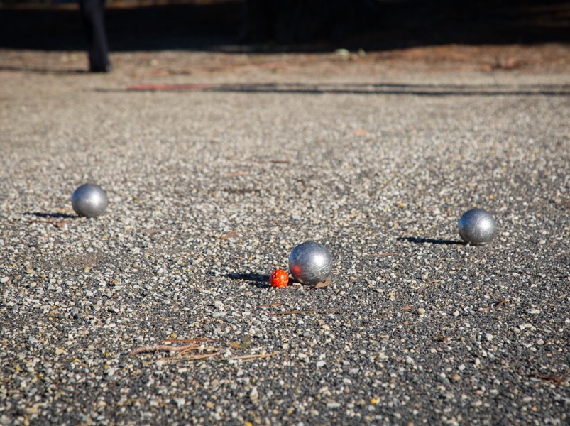 Three metal boules are thrown by each team in games of singles and doubles of petanque towards the cochonnet.