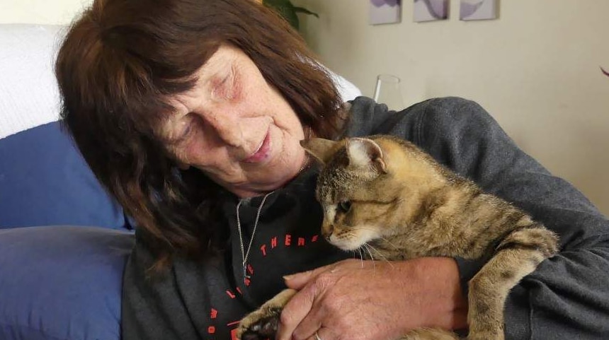 A woman cradles her cat in a living room.