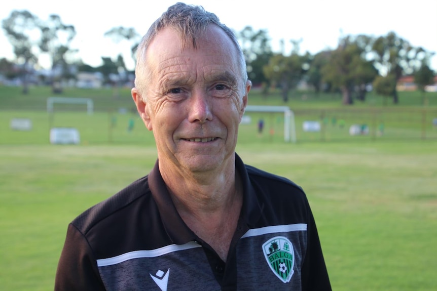 Ken Shorto smiling as he stands on a soccer field.