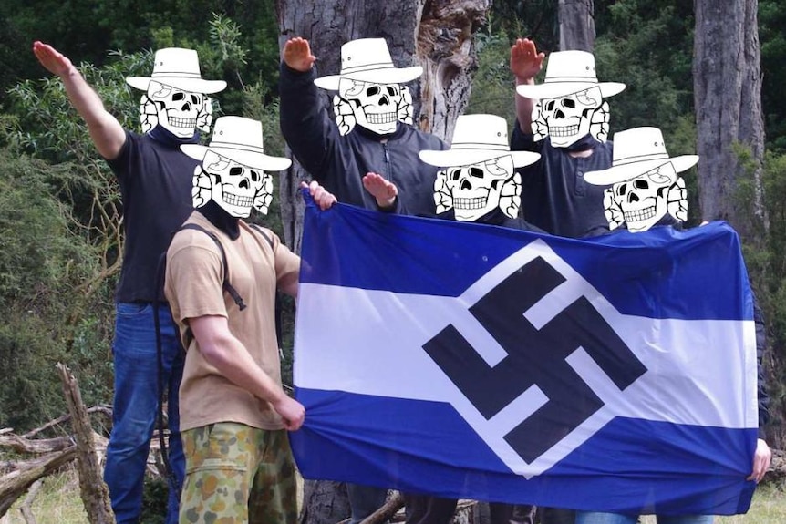 A group of young men perform a Nazi salute around a blue and white striped flag with a swastika