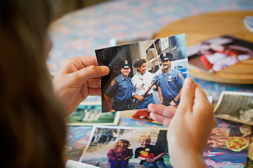 Leanne Liddle is seen holding an old photo of herself with two SA police officers.