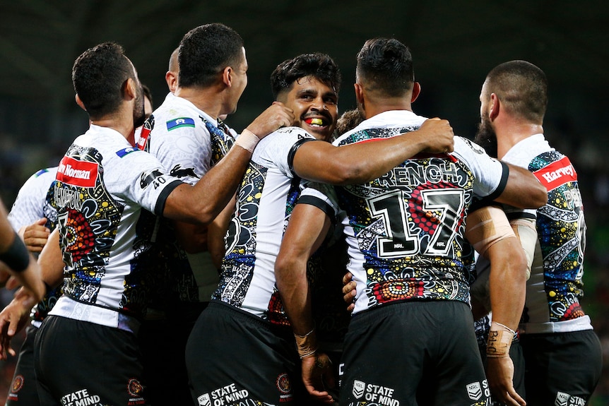 Rugby league player celebrating with their arms around each other after a try is scored