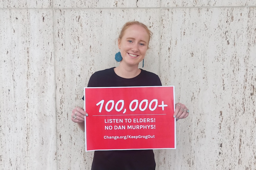 Olivia Williams holds a sign indicatng she has received over 100,000 signatures for her petition against a new Dan Murphys.