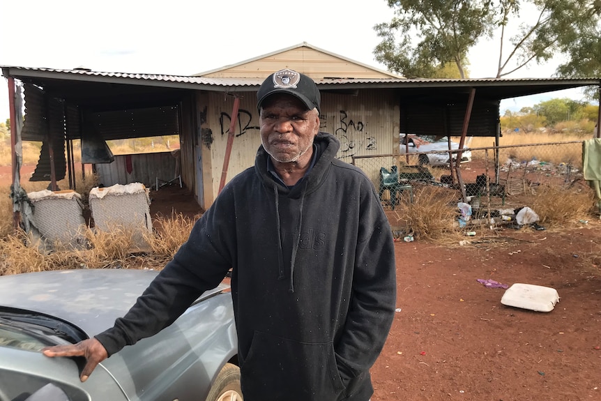 Dion Williams stands in front of a tin shack.