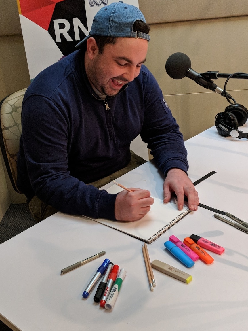 A man sketching on a pad in an ABC studio.