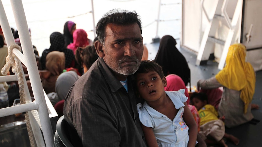 A Rohingya refugee holds a young child.