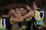 Dion Prestia and two Tigers teammates give each other high fives as they celebrate a goal against Essendon.