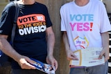 Two volunteers wearing Yes and No campaign shirts stand next to each other with their faces cropped out.