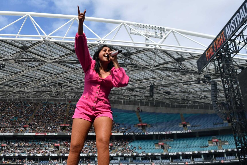 Jessica Mauboy raises her hand as she sings at Sydney's Olympic stadium