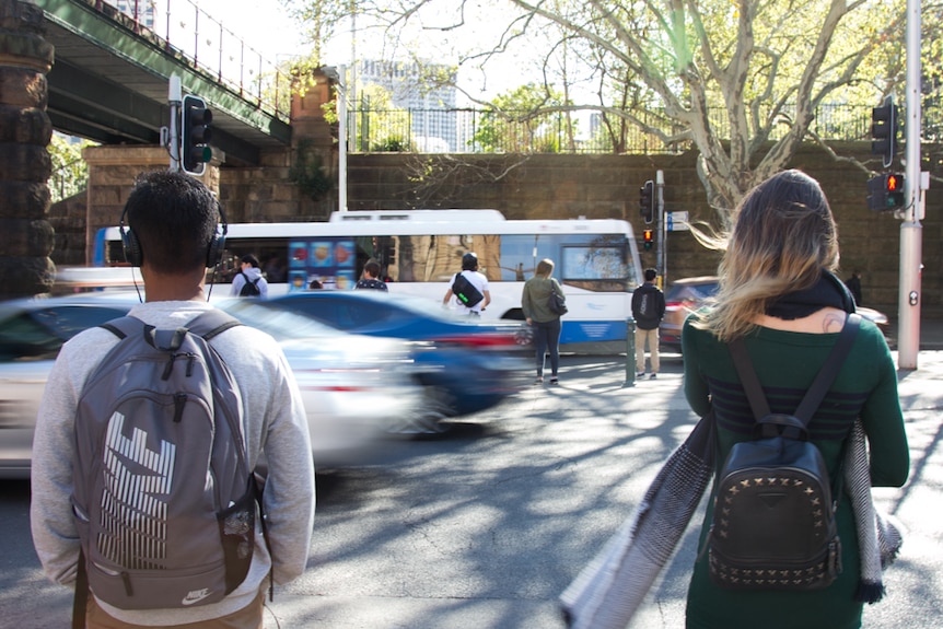 Two people stand waiting to cross at the pedestrian crossing