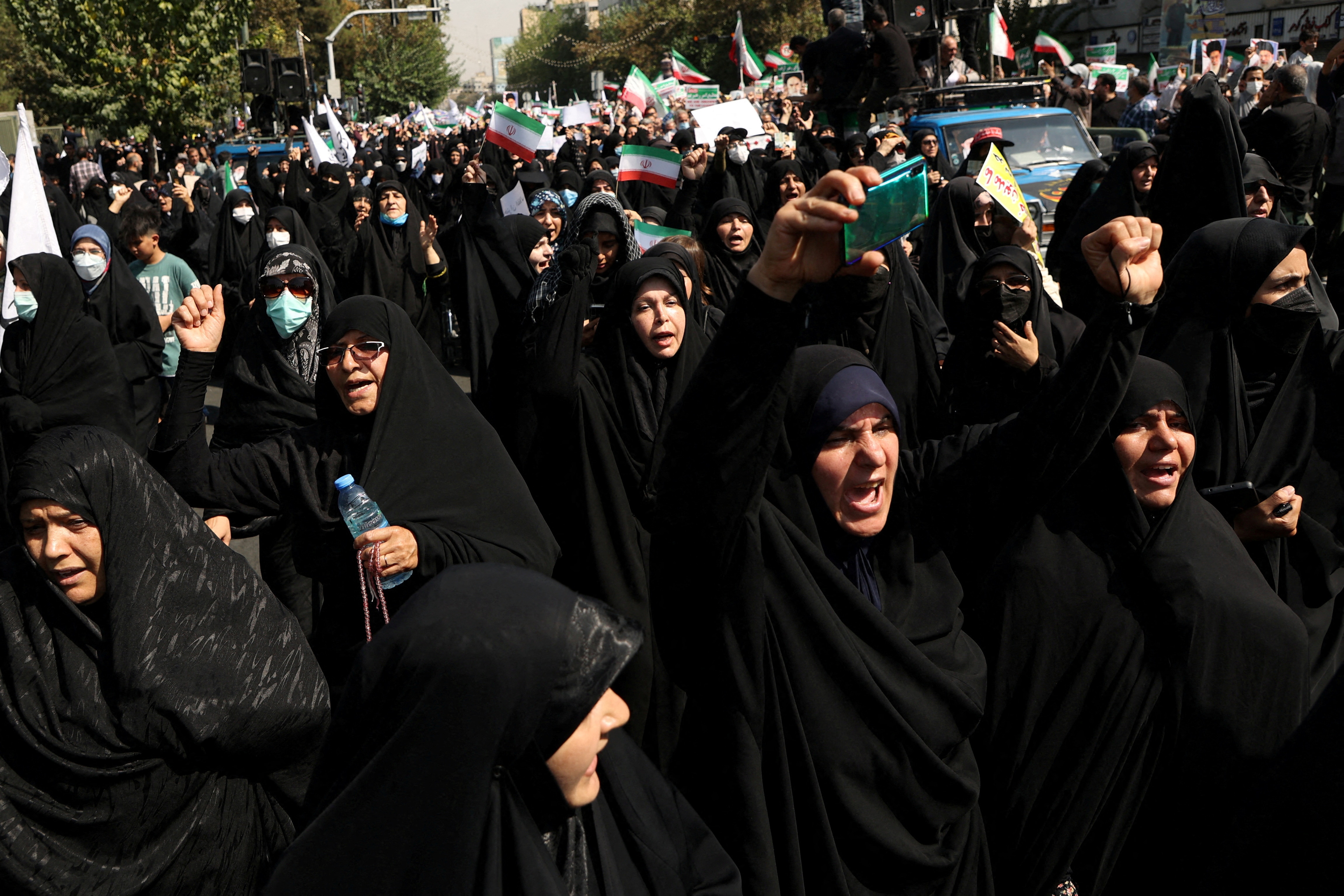 A large group of female protesters dressed in black chadors at a protest. 