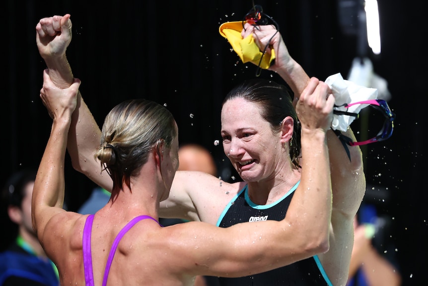 Cate Campbell cries while Bronte Campbell holds her arms up beside the pool