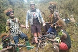A pilot stands beside heavily-armed rebels in Papua.
