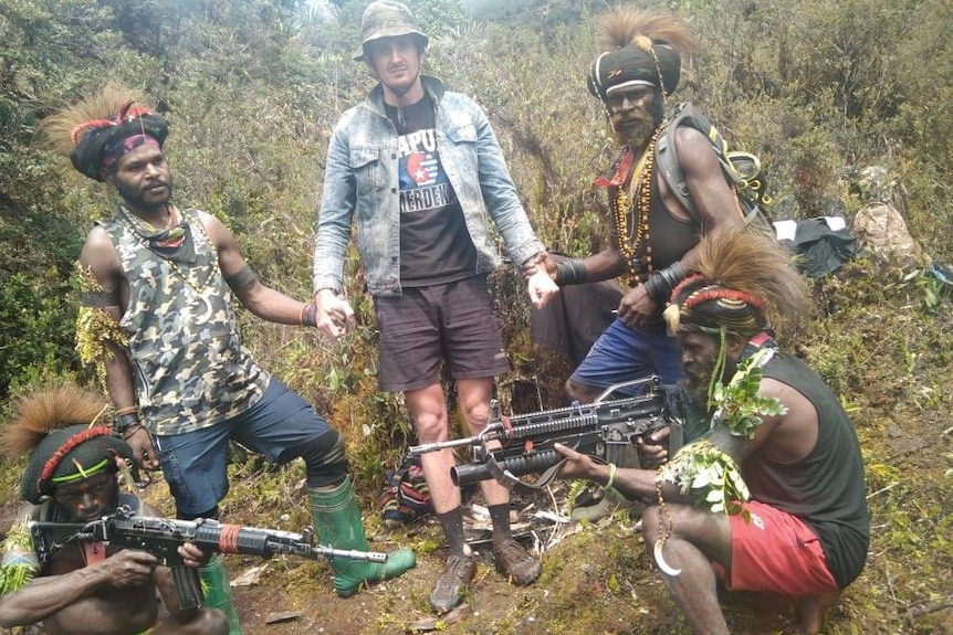 A pilot stands beside heavily-armed rebels in Papua.