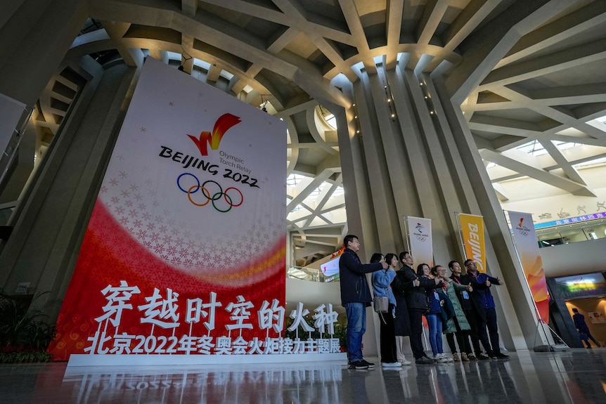 People pose near a Beijing 2022 Winter Olympic Games decoration
