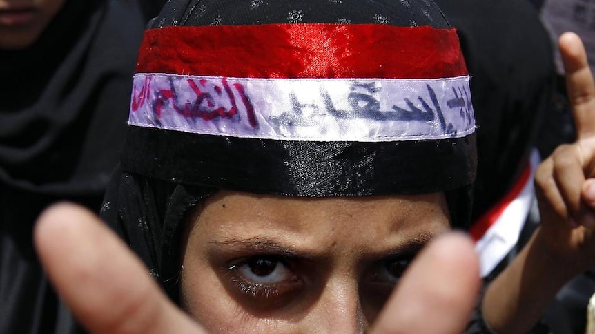 A Yemeni anti-government protester shows her palms with a message written on them
