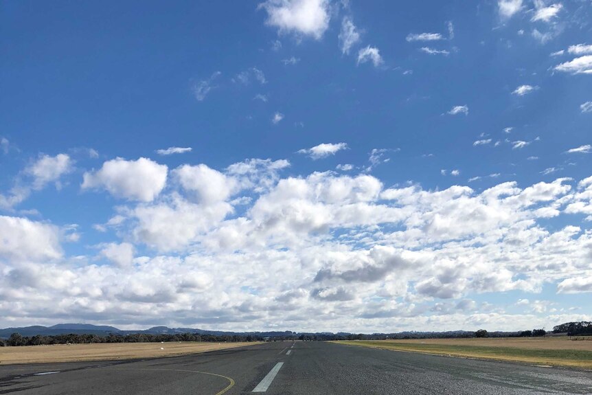 An empty runway beneath a blue sky at a regional airport.