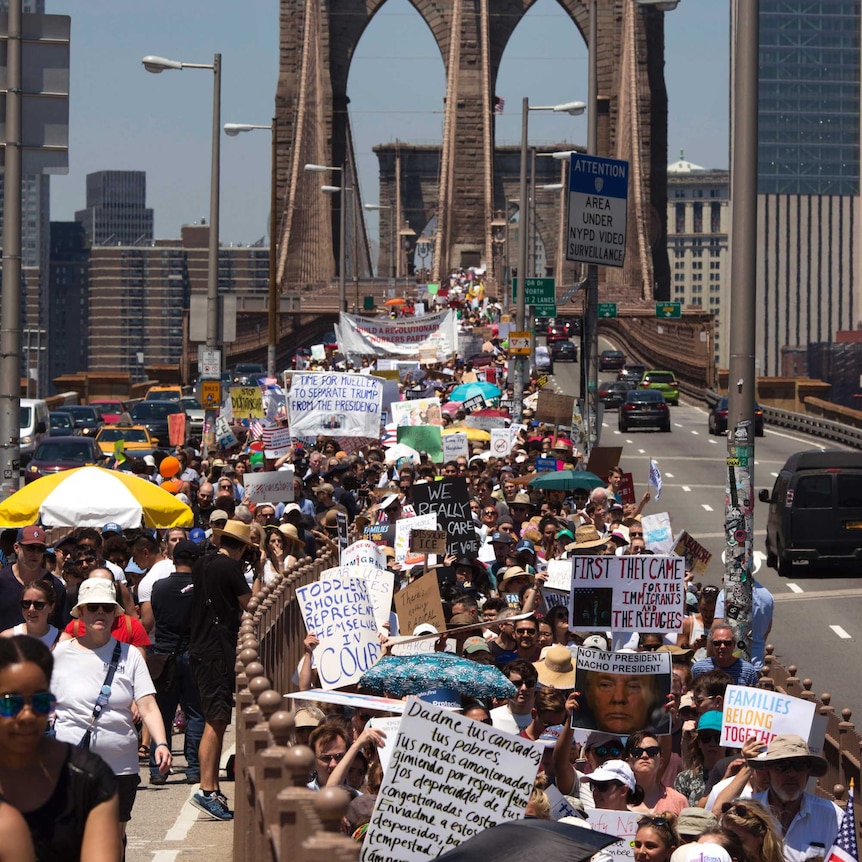 Activists carry signs across the Brooklyn Bridge