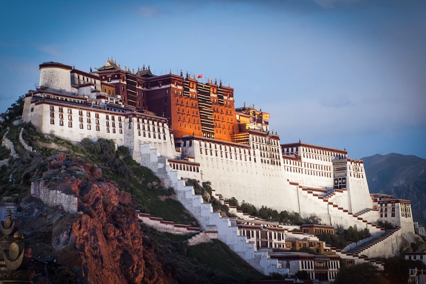 An expansive palace set on a hilltop is seen at sunset