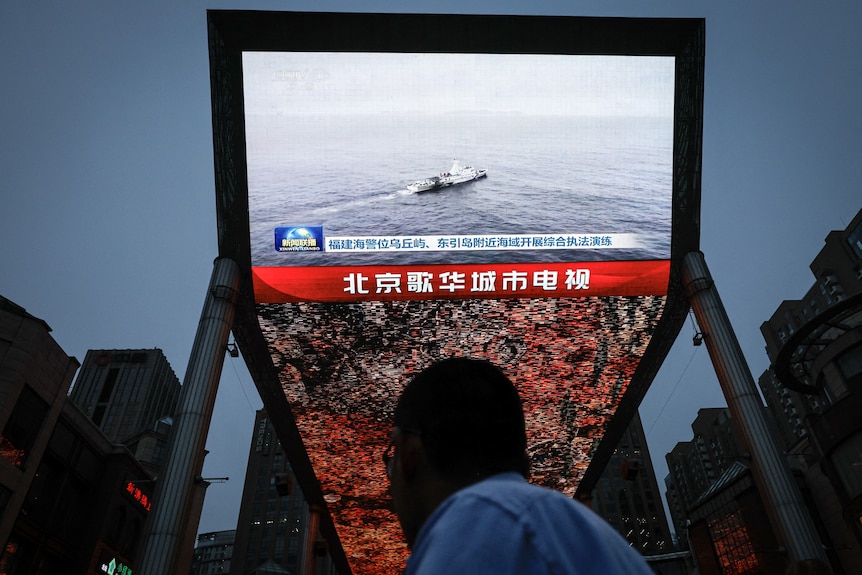 A person stares at a television screen where a boat is floating in an ocean of water.