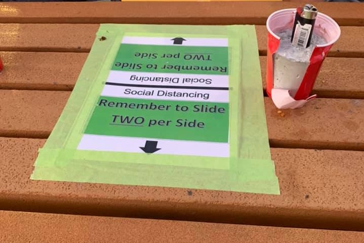 A tabletop displays signs that say only two people can sit on each side of the table.