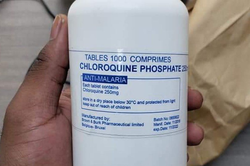 A hand hold a white plastic tablet bottle with a label saying Chloroquine Phospate