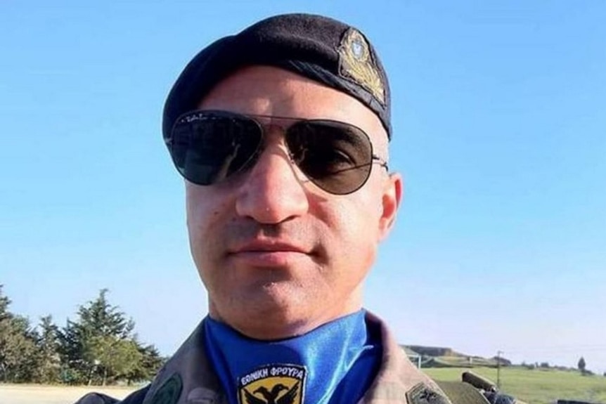 A man wearing sunglasses, a beret and a military uniform poses for a photograph