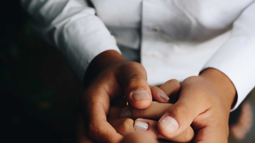 A man in a white coat holding someone's hands